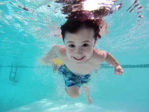 kid smiling as he swims underwater